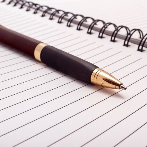Image shows a notepad with a pen, intended to demonstrate note-taking. 